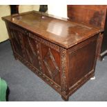An 18th century carved oak coffer with three panelled diamond pattern front and scrolled frame on