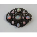 An opal brooch, set with eleven opal cabochons in a closed back setting, in white metal