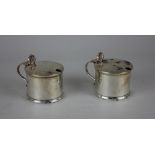 A pair of modern silver mustard pots cylindrical shape with blue glass liners, shell cast thumb