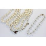 An opera length cultured pearl necklace with a diamond and ruby set clasp in a trefoil design with