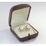 A pair of pearl and diamond stud earrings, each cultured pearl surrounded by a halo of single cut