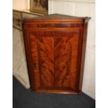 A George III mahogany hanging corner cupboard with single crossbanded flame vennered door