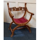 An X framed hall chair with pierced floral carved bar back and scroll arms