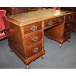 A 20th century writing desk with leather inset rectangular top above an arrangement of seven drawers