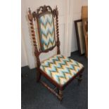 A Victorian nursing chair with scroll carved cresting rail above barley twist supports and padded