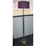 An adjustable brass standard lamp with column support on circular base and three feet