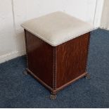 An early 20th century oak box stool with upholstered rising top, beaded corners, on four metal paw