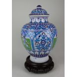 A Middle Eastern jar and cover with panels of figures amongst blue and green floral decoration, 40cm