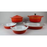 A Le Creuset orange enamel oval casserole dish and cover 27cm, two circular Le Creuset dishes