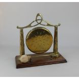 A brass table top dinner gong on wooden stand with clanger, 25.5cm