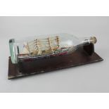 A model four-masted ship 'La Mouette' inside a glass bottle, on wooden stand bottle 33cm long