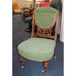 An Edwardian nursing chair with green upholstered back pad and seat on turned legs and castors
