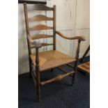 An oak ladderback armchair with rush seat on turned supports