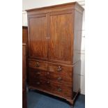 A George III mahogany linen press cupboard with panelled doors enclosing four sliding trays on