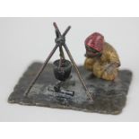 A Bergman style cold painted bronze of a figure beside a camp fire, verso initialled 'HK' 4cm high