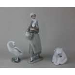 Three Lladro porcelain figures of a woman holding a chicken and a basket 24.5cm high, a polar bear
