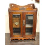 An oak smokers cabinet with two glazed panel doors enclosing shelf and two drawers, with silver
