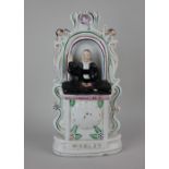 A Staffordshire pottery figure of John Wesley preaching from his pulpit, with clock face 29.5cm high