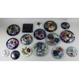A collection of sixteen Moorcroft pottery covers for jars and pots, in various patterns largest 17cm