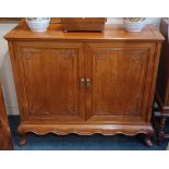 A Chinese hardwood side cupboard, with two leaf carved panel doors enclosing shelf, on cabriole