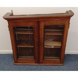 A Victorian mahogany wall cabinet with slanted top and two glazed panel doors enclosing two shelves,