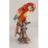 A porcelain model of a parrot perched on a trunk formed as a bud vase 34cm high (a/f)