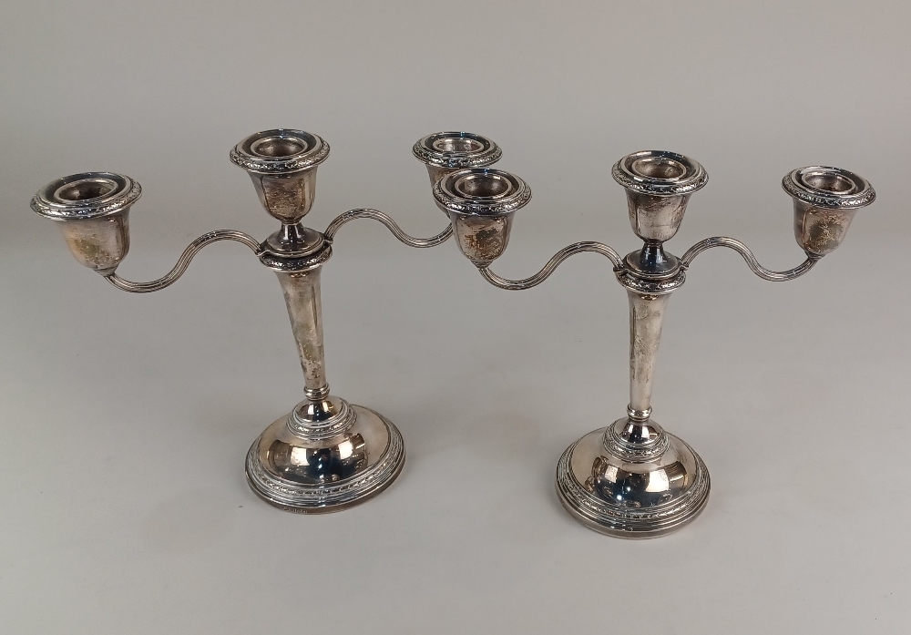 A pair of Elizabeth II silver three branch candlesticks on loaded bases, maker Adie Brothers Ltd,