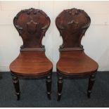 A pair of Victorian mahogany hall chairs, with scroll and shield shaped back and solid seat on