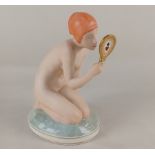 A Royal Copenhagen porcelain figure of a nude holding a hand mirror and kneeling on an oval base,