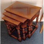 A nest of three oak side tables, each with rectangular top on turned supports with low uniting