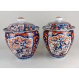 A pair of Japanese Imari porcelain jars and covers, decorated with panels of birds and flowers