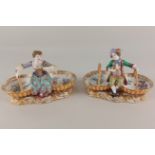 A pair of 19th century porcelain figural salts, modelled as a lady and gallant seated upon two