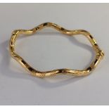 A wavy hinged bangle, in a textured tubular design, with safety clasp