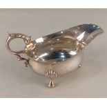 A George V silver sauce boat with flying scroll handle on three shell cabriole feet, maker