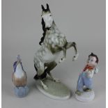 A Royal Dux porcelain figure of a rearing horse a Royal Dux figure of a whistling boy and a