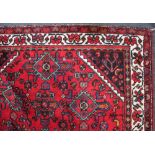 A Persian style wool rug red floral ground with cream lozenge centre, 139cm by 227cm