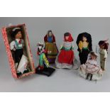 A collection of twenty one various costume dolls, together with a small leather suitcase