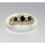 A dark sapphire three stone ring, set with four small diamonds, in 9ct gold, 2.4g