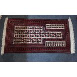 A Persian wool prayer rug central shaped panel of geometric leaf motifs with black red multiguard