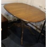 An Ercol extending oval dining table with fold away extending leaf, on baluster stem and four scroll