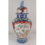 A large Imari porcelain vase and cover, the baluster body decorated with panels of flowers, trees
