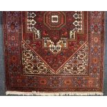 A Persian wool rug with crimson lozenge centre, label marked Ghoitagh, 100cm by 150cm