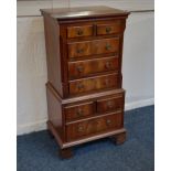 A reproduction mahogany small chest on chest cabinet with eight various drawers, on bracket vase,