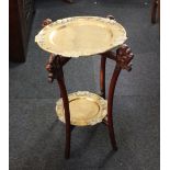 A Chinese two-tier brass plate occasional table with carved wooden supports, height 59cm