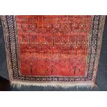 A Persian wool rug with geometric floral design on red orange ground, 117cm by 172cm