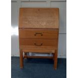 A light oak small bureau with two drawers and brass drop handles on square legs, 62cm