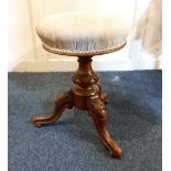 A Victorian carved walnut circular piano stool with adjustable upholstered seat on tripod base,