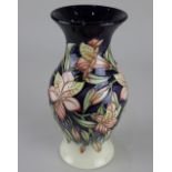 A Moorcroft pottery vase with peach coloured flowers on blue and cream ground 19.5cm high