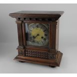 An oak cased mantle clock the dial with silvered chapter ring and Roman numerals, striking on a