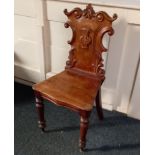 A Victorian carved hall chair with scroll frame back and solid seat